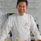 A chef stands in a clean ktichen.