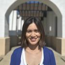 A photo of a woman with an outdoor arch behind her.